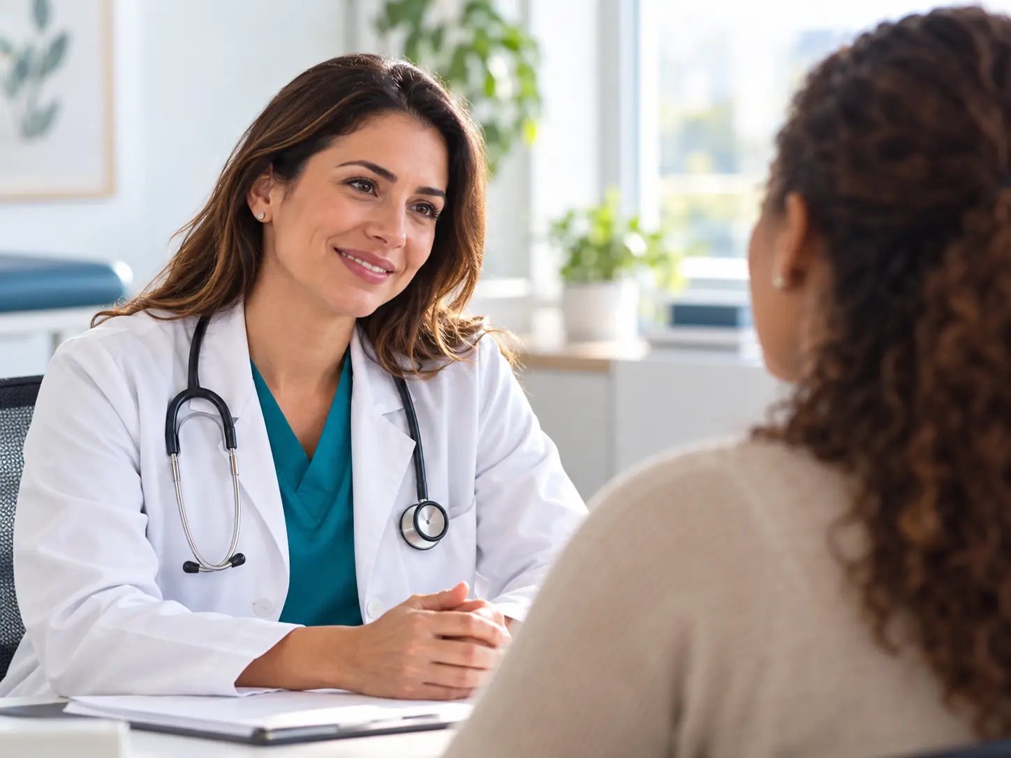 Médica sorrindo enquanto conversa com uma paciente